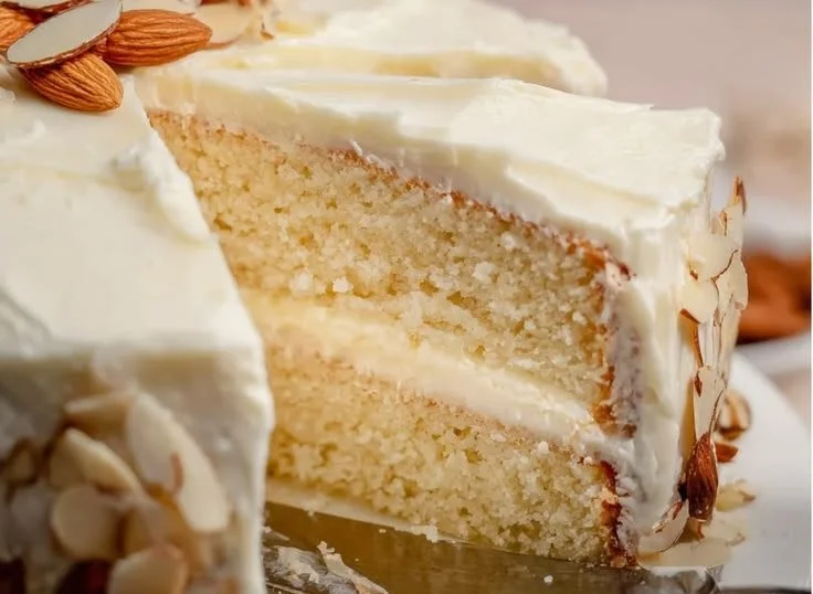 Slice of almond cream cake with creamy frosting and almond decorations