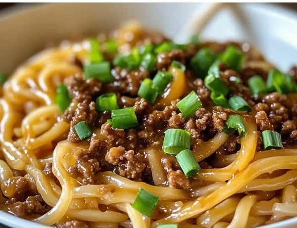 Mongolian beef noodle stir-fry served in a bowl with fresh vegetables.